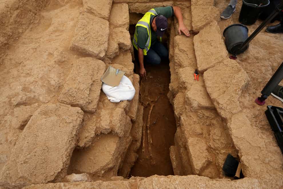 An archaeologist removes sand from a skeleton in a grave at the Roman cemetery (AP/Adel Hana)