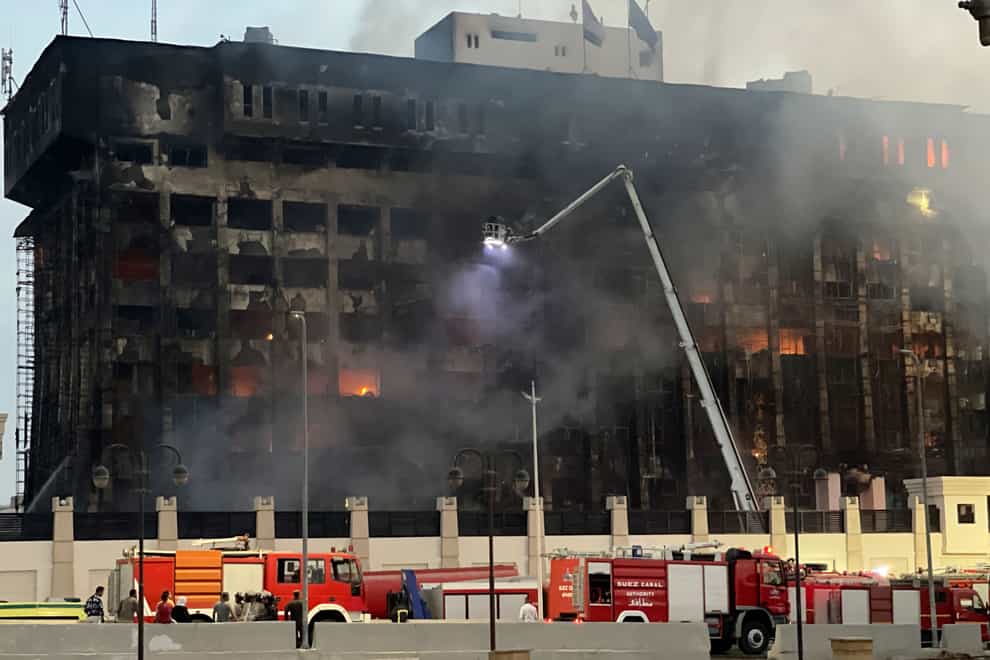 Firefighters climb up a ladder on the burning building of the police headquarters in Ismailia (AP Photo)