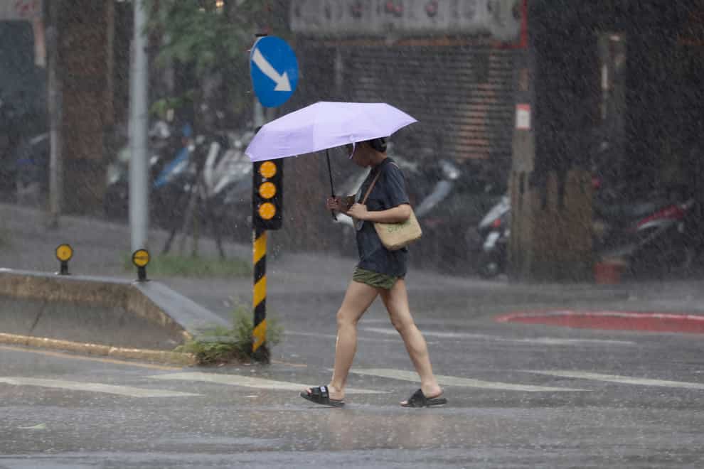 A woman walks in the rain as Typhoon Koinu approaches to Taiwan in Taipei (Chiang Ying-ying/ AP)