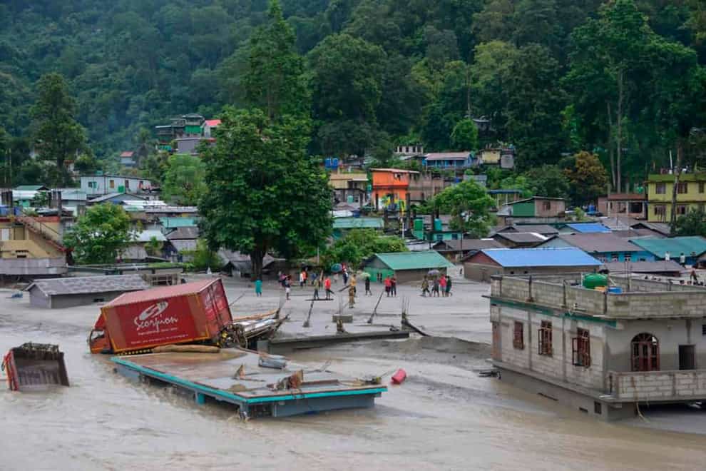 A truck lies on top of a submerged building after flash floods triggered by a sudden heavy rainfall in north-east India (Prakash Adhikari/AP/PA)