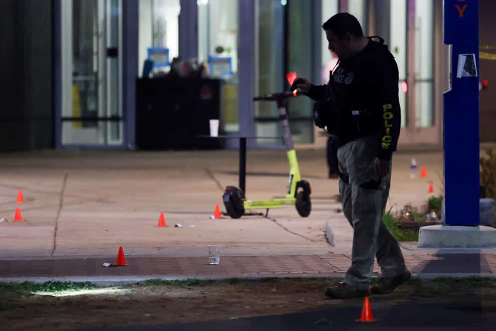 A police officer searches for evidence in front of a building at Morgan State University after a shooting injured five people (Julia Nikhinson/AP/PA)