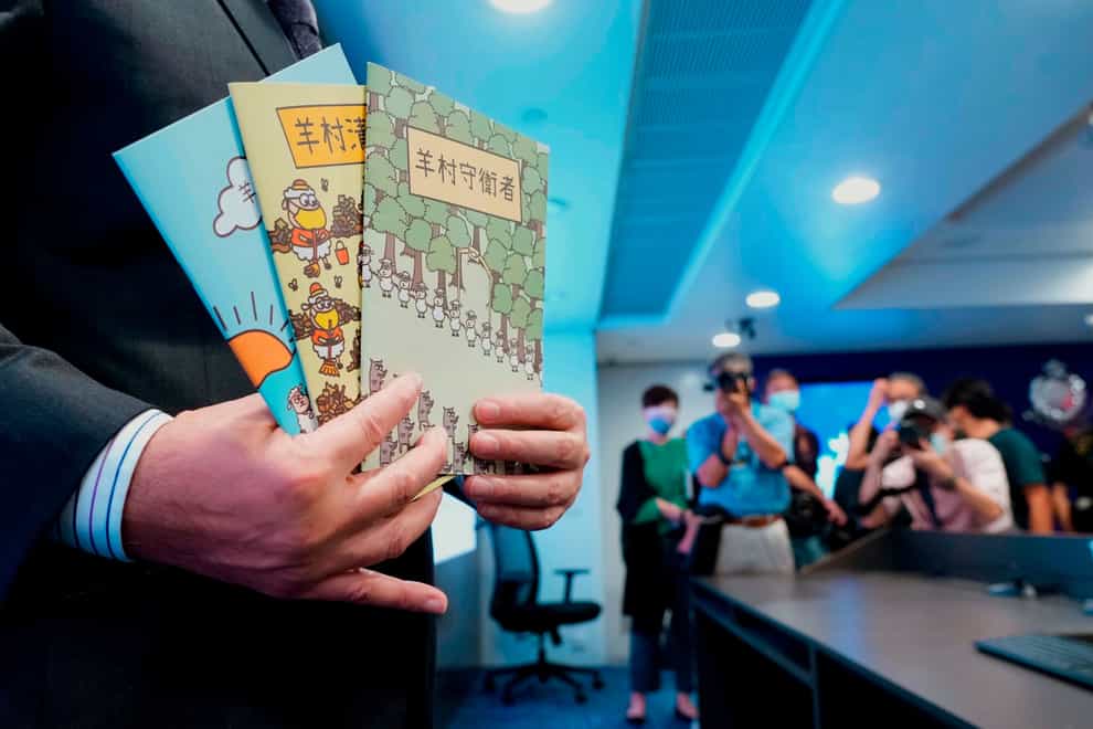 A policeman holds up the three books that were considered to be ‘seditious’ (AP Photo/Vincent Yu, File)