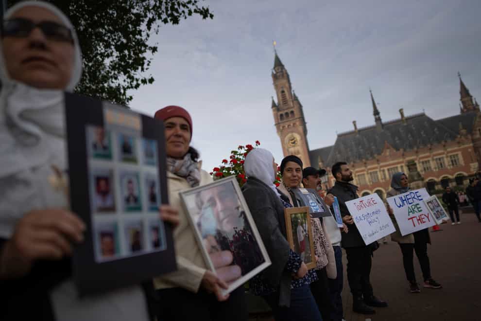Demonstrators outside the World Court hold pictures of people they say disappeared in Syria (AP Photo/Peter Dejong)