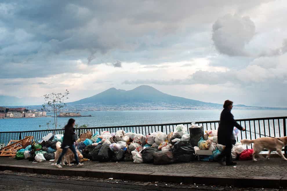 People walk past uncollected rubbish in Naples, Italy, in 2010 (Salvatore Laporta/AP)
