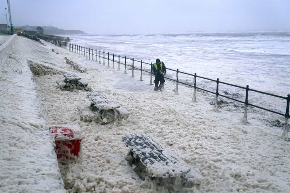 A man walks through sea foam in Seaburn, Sunderland, as Storm Babet batters the country (Owen Humphreys/PA)