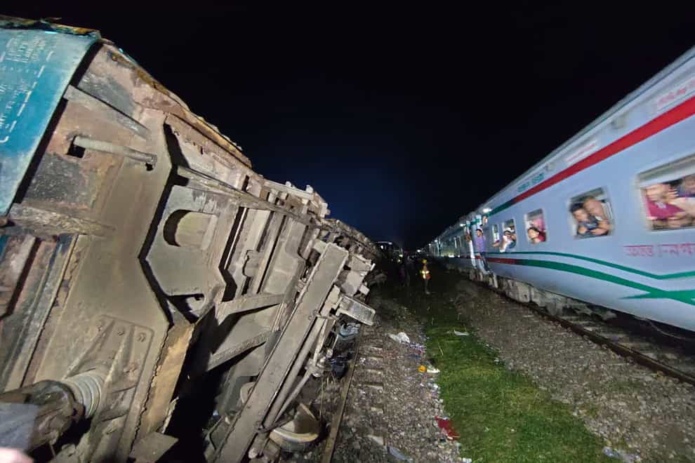 Passengers of a passing train view the crashed compartments (Mahmud Hossain Opu/AP)