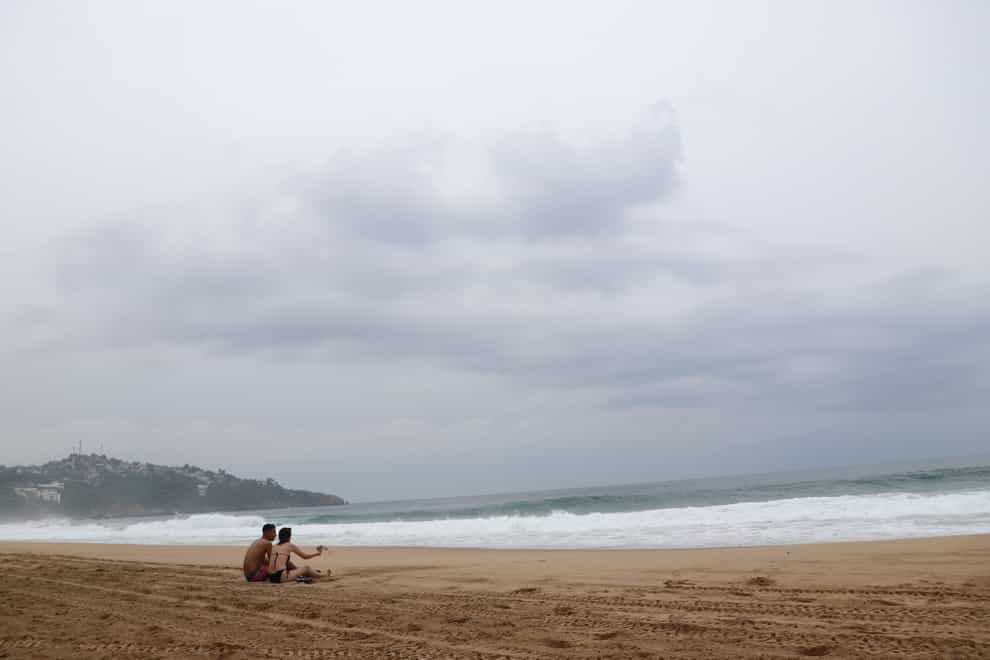 Tourists sit on the beach in Acapulco, Mexico (Bernardino Hernandez/AP)
