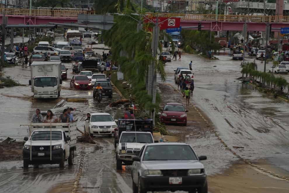 Cars cross a flood-damaged avenue after Hurricane Otis hit Acapulco, killing at least 27 people (Marco Ugarte/AP)