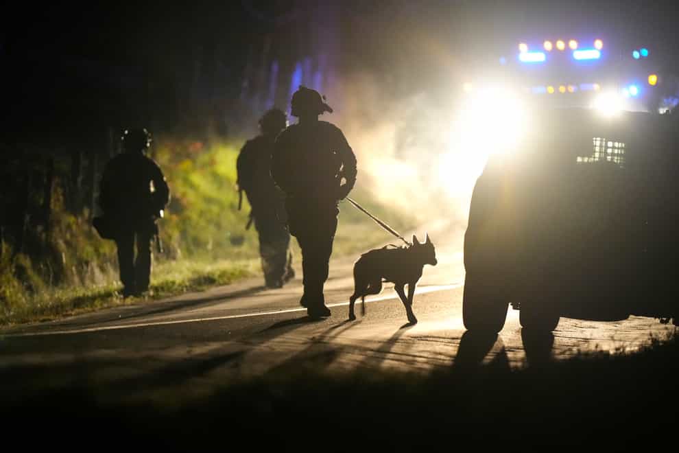 A member of law enforcement walks with a police dog outside a property on Meadow Road, in Bowdoin, Maine (Steven Senne/ AP)
