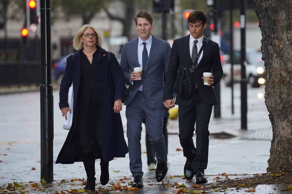 Dustin Lance Black, centre, arrives at Westminster Magistrates’ Court, with his husband Tom Daley, right (Lucy North/PA)
