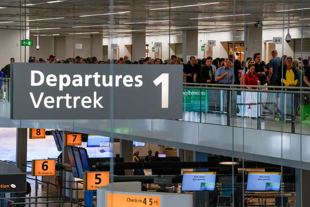 Travellers wait to check in and board flights at Amsterdam’s Schiphol Airport (Peter Dejong/AP)