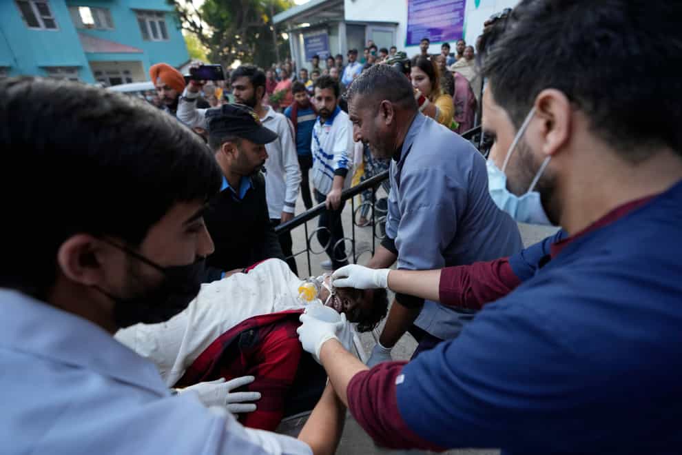 A man injured after a passenger bus slid off a Himalayan highway is brought to hospital for treatment (AP)