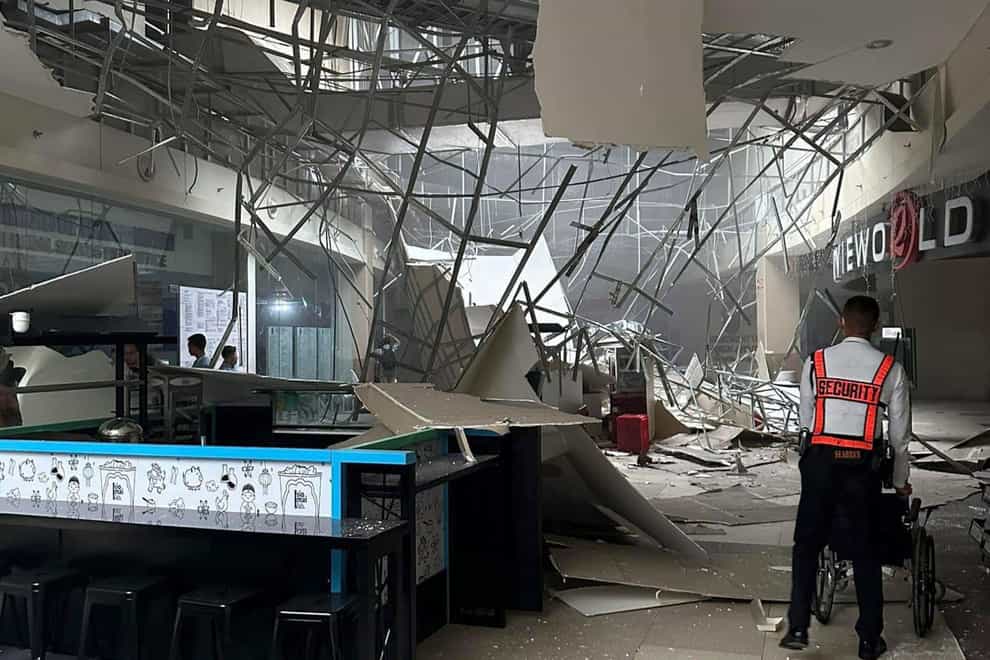 A security guard walks beside the damaged ceiling of a shopping mall in General Santos City, South Cotabato (AP)