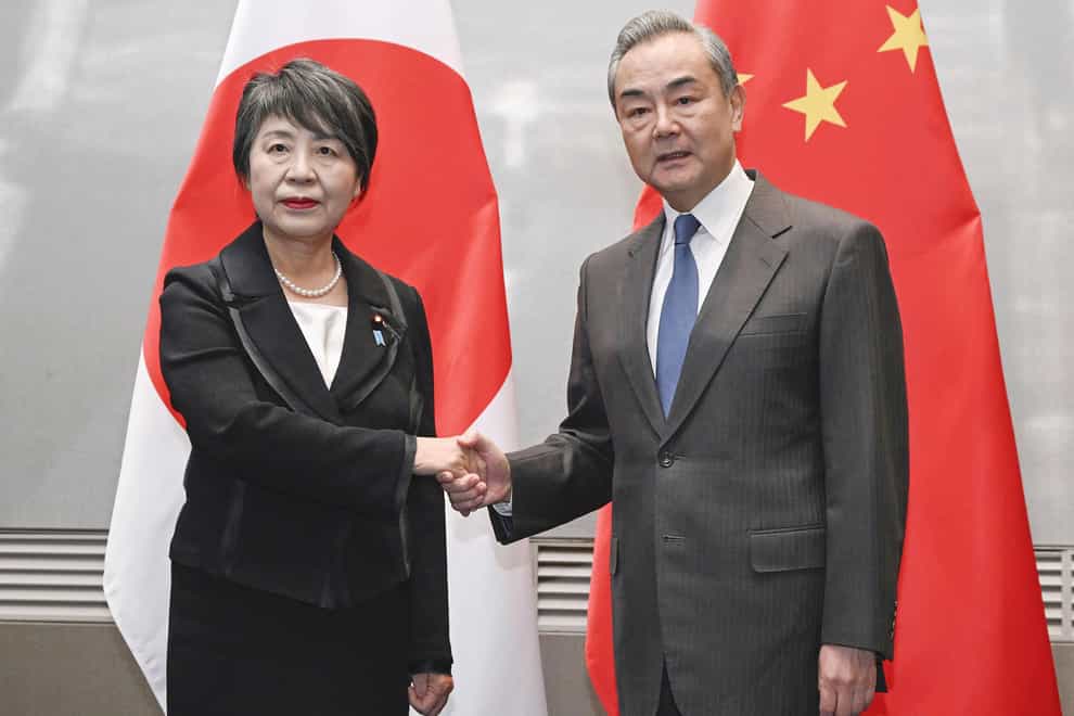 Japanese foreign minister Yoko Kamikawa, left, and her Chinese counterpart, Wang Yi, shake hands during their bilateral talk (Kyodo News via AP)