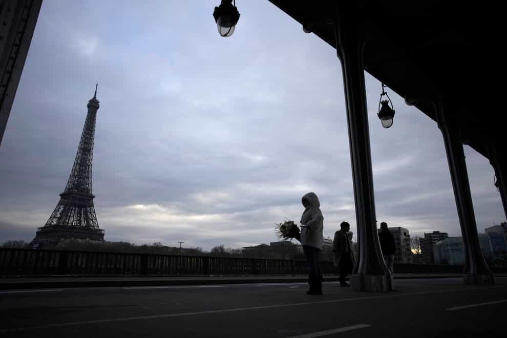 Tourists stand at the site in Paris where a man targeted passers-by, killing a German tourist with a knife and injuring a British man (Christophe Ena/AP)