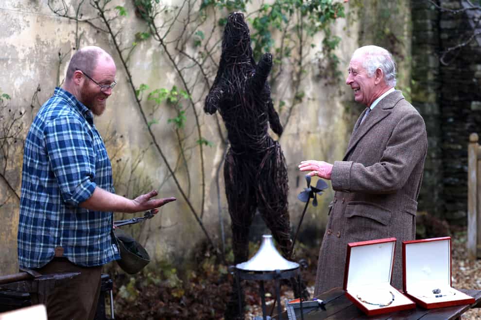 Charles laughs with Ian Thackray, a blacksmith who realises his hands are too dirty to shake hands (Adrian Dennis/PA)