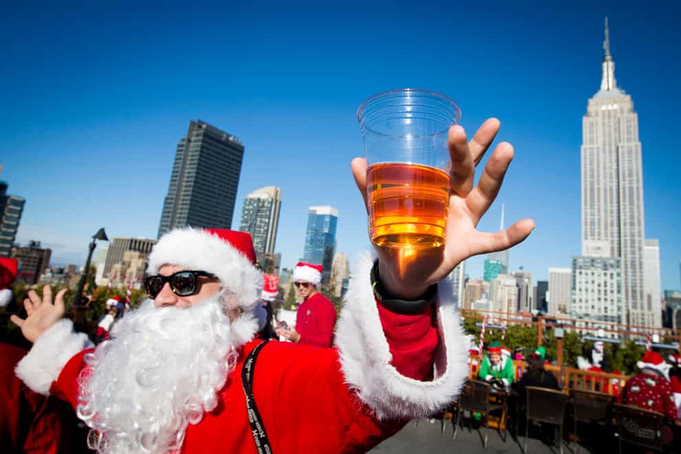 A man dressed as Santa Claus holds a beer as he and others participate in SantaCon (John Minchillo/AP)