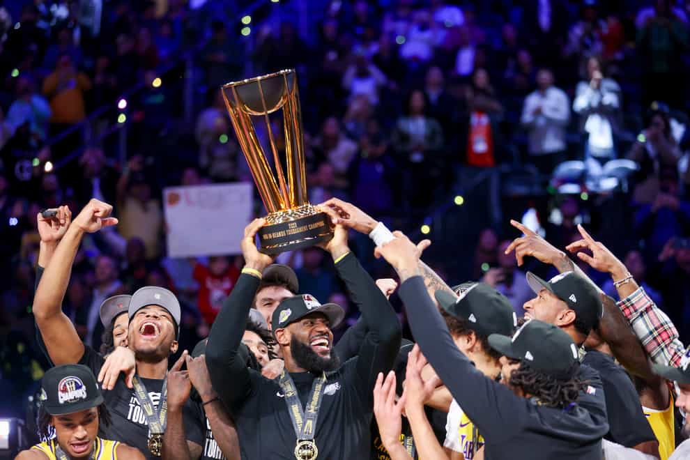 Los Angeles Lakers forward LeBron James, centre, lifts the NBA Cup while celebrating with teammates (Ian Maule/AP)
