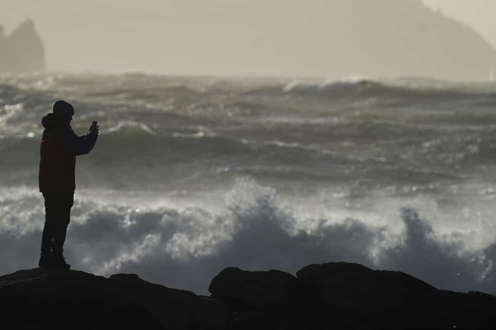 A person watching high waves in Doolin in County Clare on the west coast of Ireland (Niall Carson/PA)