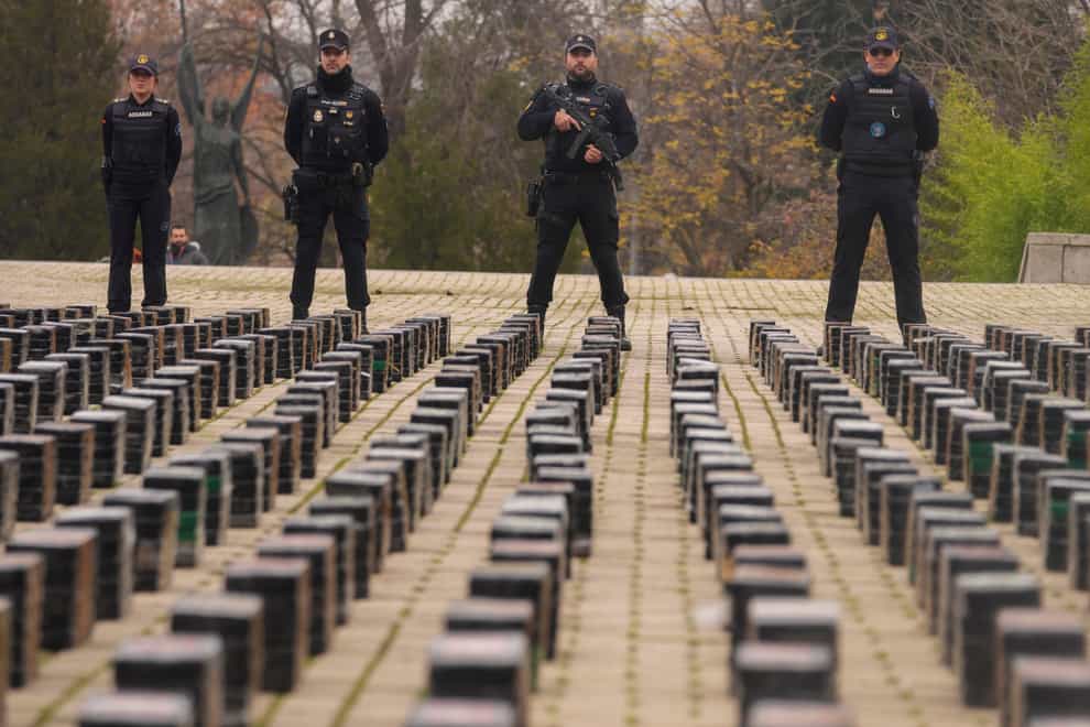 Police officers stand by part of a haul of 11 tons of cocaine, displayed in the patio of a police station in Madrid, Spain (AP Photo/Paul White)