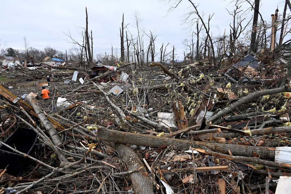 A man, left, cuts trees in the rubble of a mobile home neighbourhood in Clarksville, Tennessee (Mark Zaleski/AP)