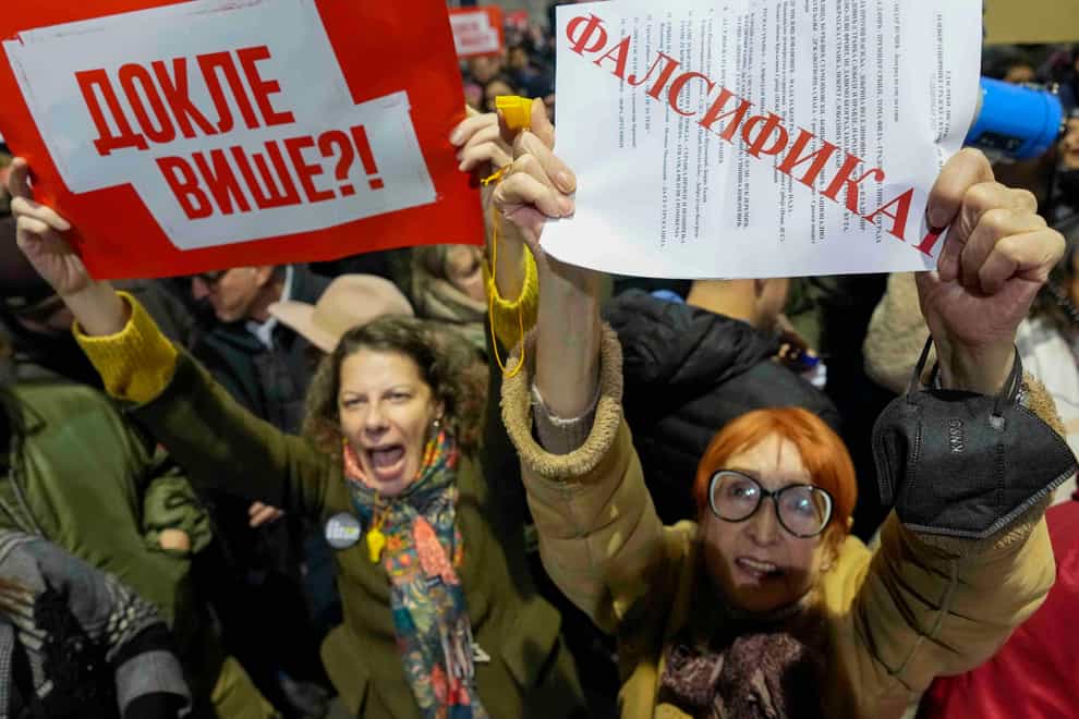 People hold copies of the ballots, reading ‘forgery’ during a protest outside the electoral commission building in Belgrade, Serbia (Darko Vojinovic/AP)