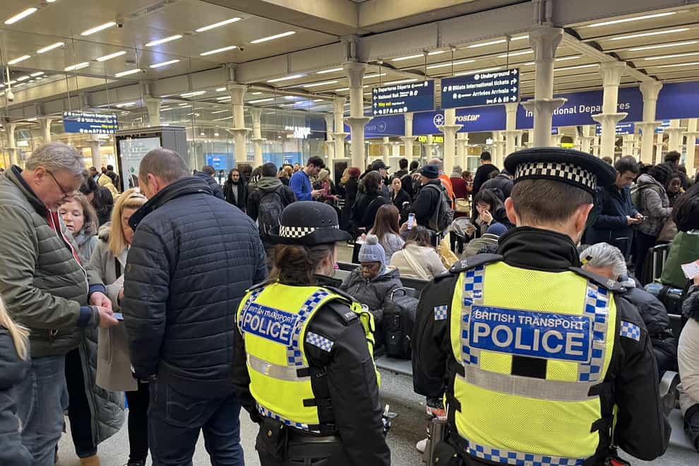 British Transport Police officers watch as passengers wait at the Eurostar entrance in St Pancras International station (Lucy North/PA)