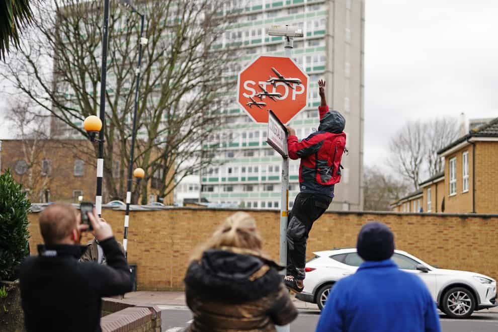 A person removes artwork by Banksy which was unveiled in Peckham, south-east London (Aaron Chown/PA)