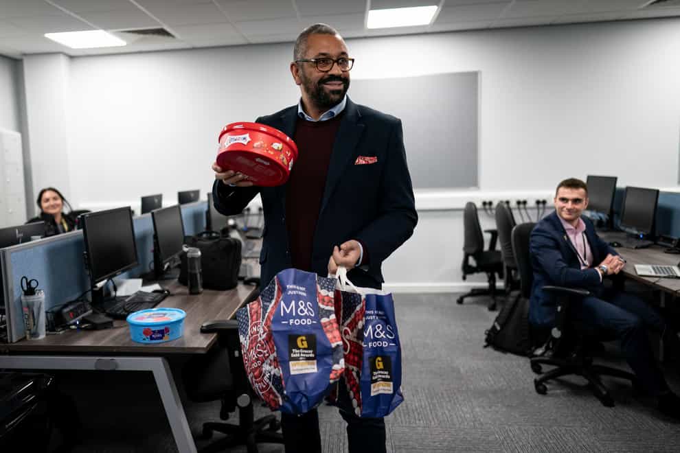 Home Secretary James Cleverly holds up a box of chocolates while meeting police officers at Luton Police Station to thank them for their serivce (PA)