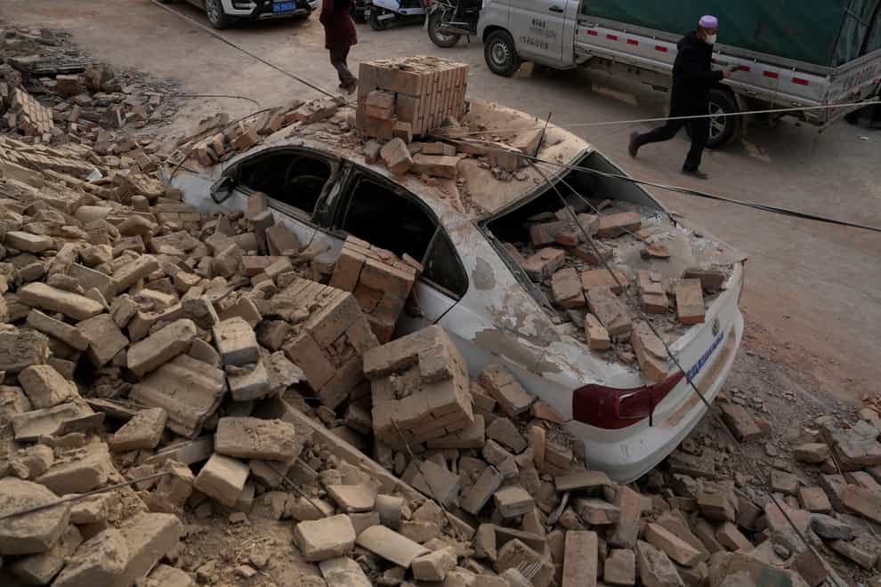 A vehicle is smashed after a brick house collapsed during an earthquake in Dahejia town in northwestern China’s Gansu province (Ng Han Guan/AP)
