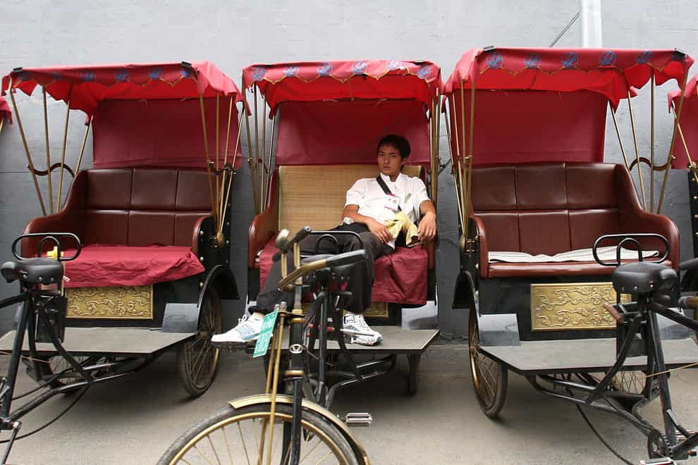 A man rests in a rickshaw near Hou Hai lake in Beijing (PA)