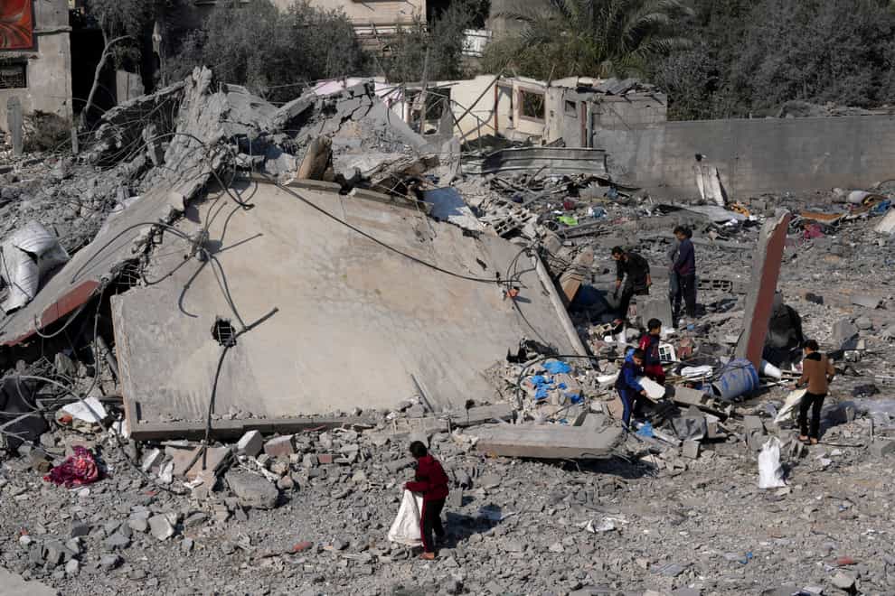 Palestinians salvage belongings from the rubble of a building destroyed in an Israeli strike in Deir al Balah, Gaza Strip on Friday (Adel Hana/AP)
