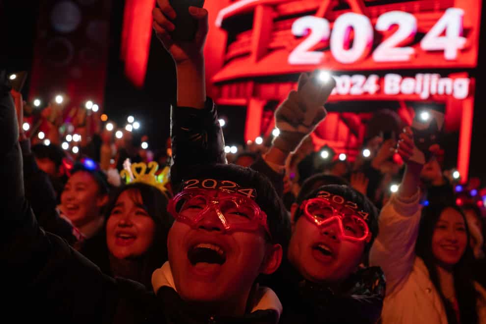 People cheer before a countdown to the new year in Beijing (Ng Han Guan/AP)
