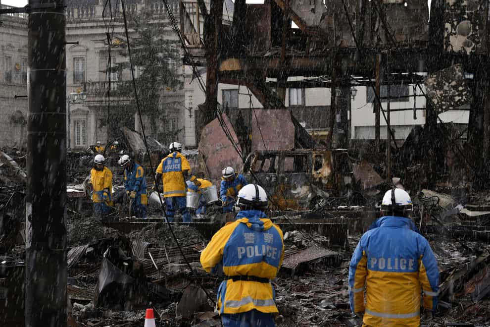 Snow falls as a search operation is continued around a burnt market in Wajima, Ishikawa prefecture (Kyodo News via AP)