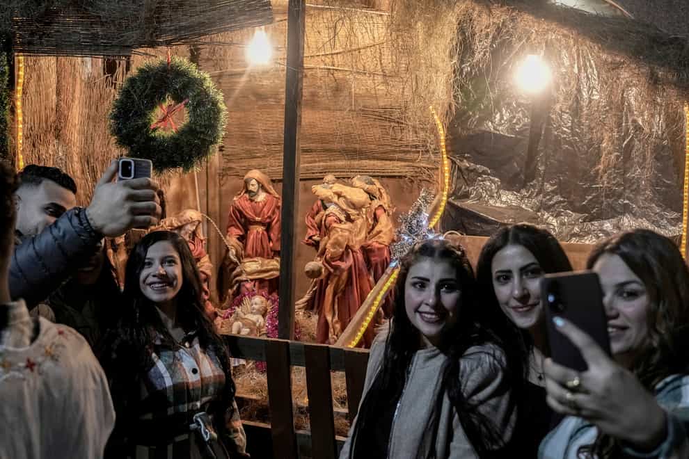 Coptic Christians pose for selfies in front of a Nativity display at the Church of Ava Bishoy and St Karas the Anchorite in Cairo, Egypt (Amr Nabil/AP)