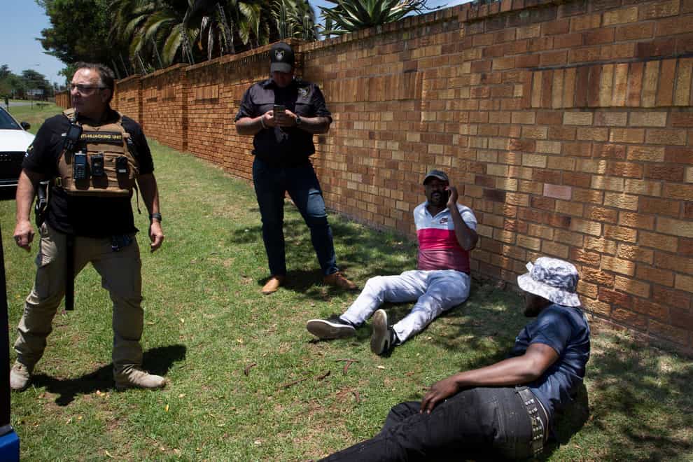 Two men, on the ground, suspected of driving a stolen vehicle, are apprehended by private security personal in a suburb east of Johannesburg, South Africa (Denis Farrell/AP)