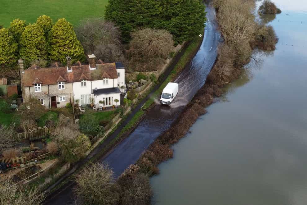A car passes through flood water from the Cuckmere River in Alfriston, East Sussex (PA)