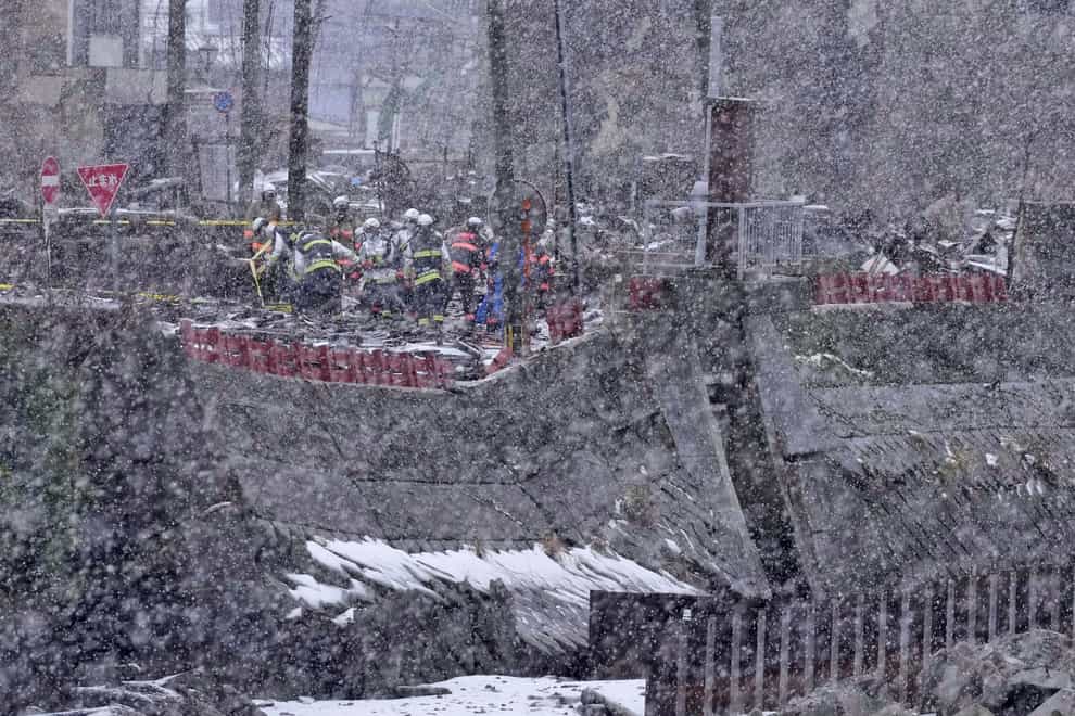 Firefighters search for missing people in the snow in Wajima, Ishikawa prefecture (Kyodo News via AP)