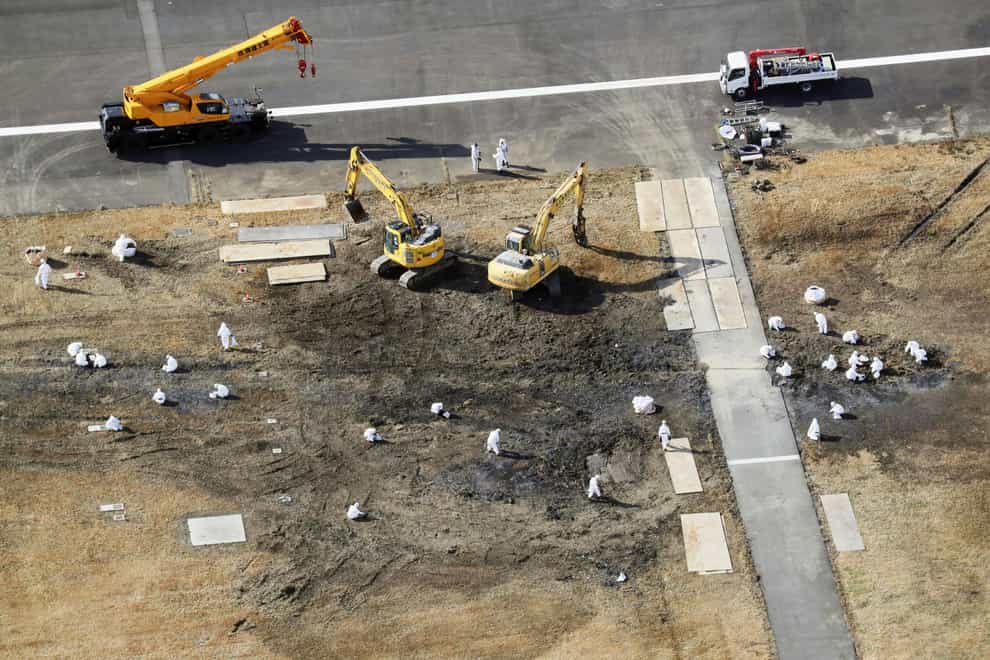 This shows workers at the site of a fatal runway crash at Haneda airport (Kyodo News via AP)
