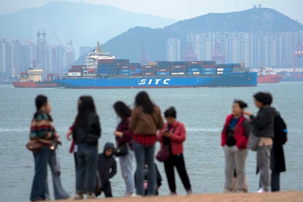 A containers vessel sails by tourists in Xiamen in southeast China as the World Bank said slumping growth in the country is likely to hurt developing countries that supply it with commodities (Andy Wong/AP)