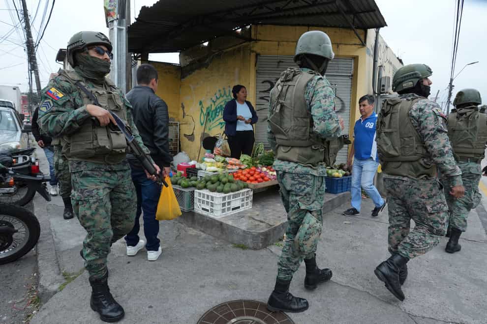 Soldiers patrol the perimeter of Inca prison during a state of emergency as a food vendor works on the sidewalk in Quito, Ecuador, Tuesday, Jan. 9, 2024, in the wake of the apparent escape of a powerful gang leader from prison. President Daniel Noboa decreed Monday a national state of emergency, a measure that lets authorities suspend people’s rights and mobilize the military in places like the prisons. The government also imposed a curfew from 11 p.m. to 5 a.m. (AP Photo/Dolores Ochoa)