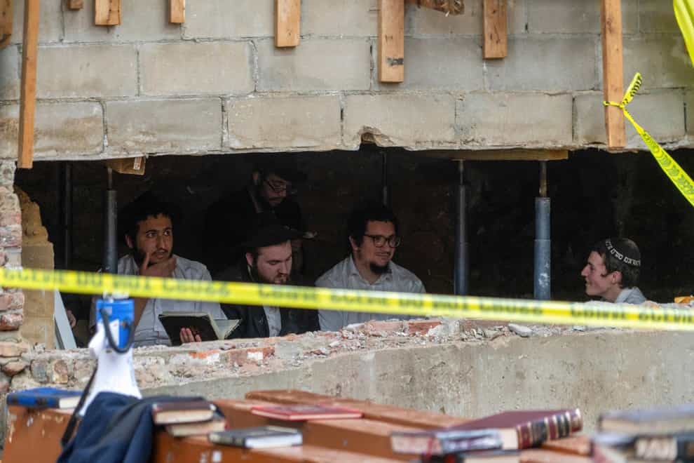 Hasidic Jewish students sit behind a breach in the wall (Bruce Schaff via AP)