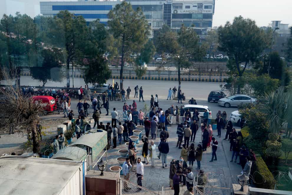 People stand outside their offices after an earthquake was felt in Islamabad (Anjum Naveed/AP)