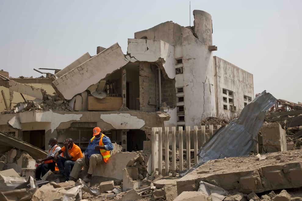 Rescue workers sit on the rubble of a building (AP Photo)