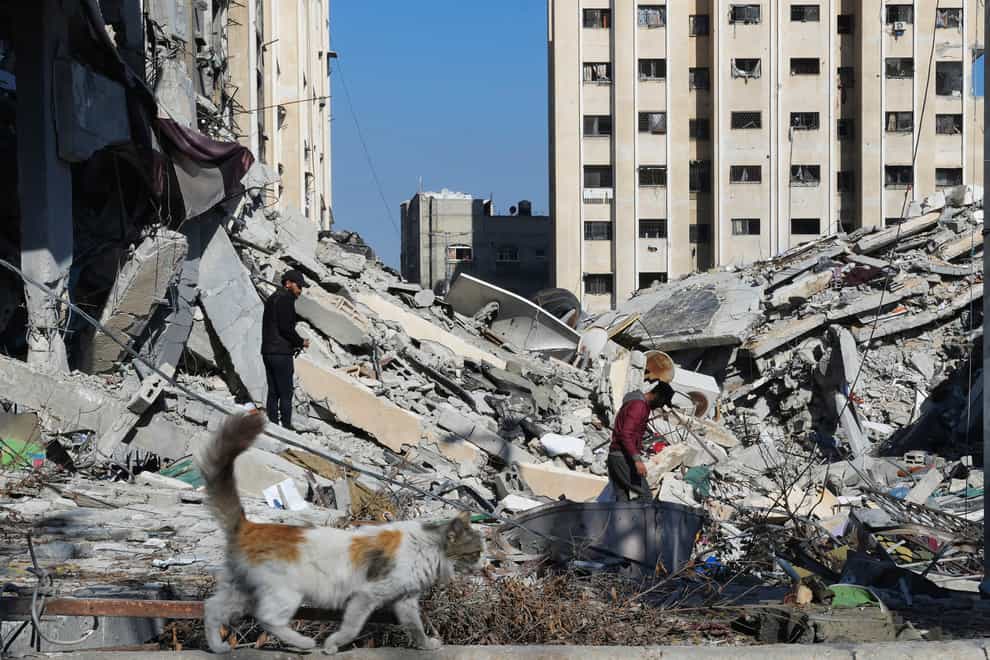 Palestinians walk through destruction from an Israeli bombardment in the Nusseirat refugee camp in Gaza Strip on Friday (Adel Hana/AP)