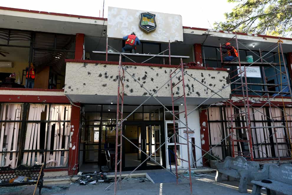 Workers repair the entrance of City Hall, riddled in large bullet holes in Villa Union, Mexico, in 2019 after 22 people were killed in a gun battle between a drug cartel and security forces (Eduardo Verdugo/AP)