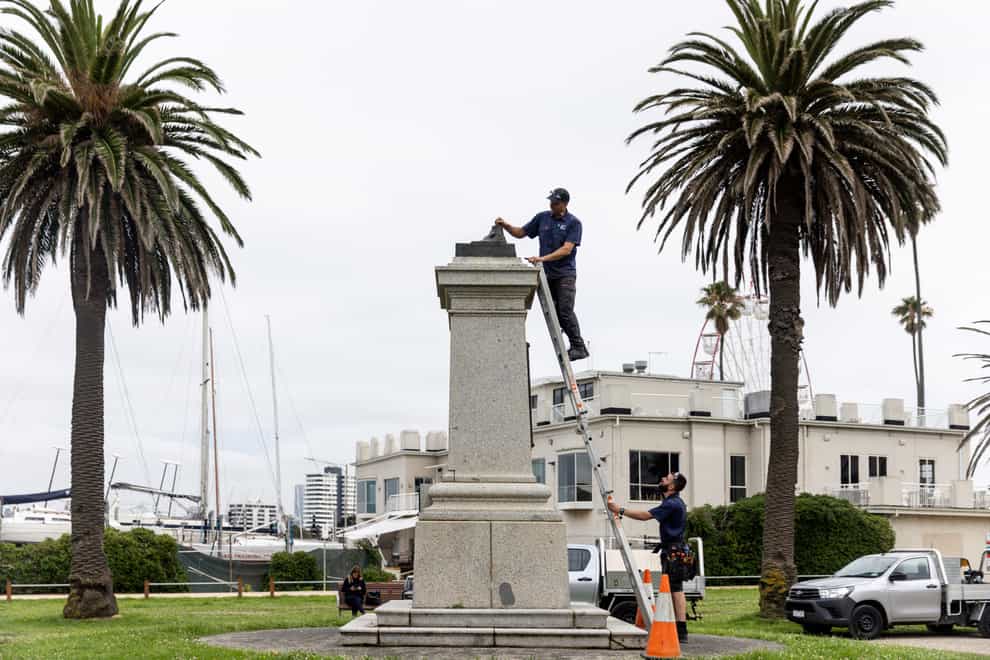 Workers remove the remnants of a Captain Cook statue in Melbourne, after vandals cut the statue off at the ankles (Diego Fedele/AAP/AP)
