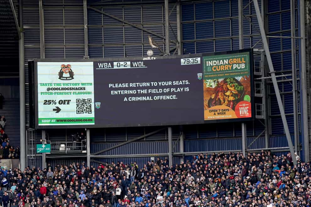 The stadium’s big screen displays a message asking for fans to return to their seats (Bradley Collyer/PA)