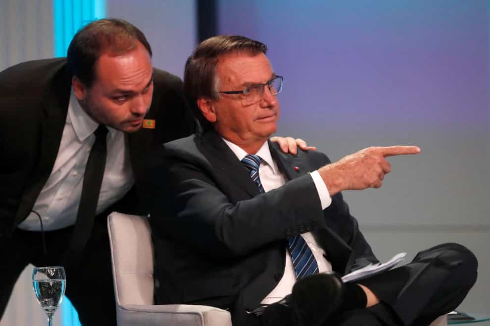 Carlos Bolsonaro, son of Brazil’s ex-president Jair Bolsonaro, whispers in his father’s ear during a presidential debate in Rio de Janeiro, Brazil, in 2022 (Bruna Prado/AP)