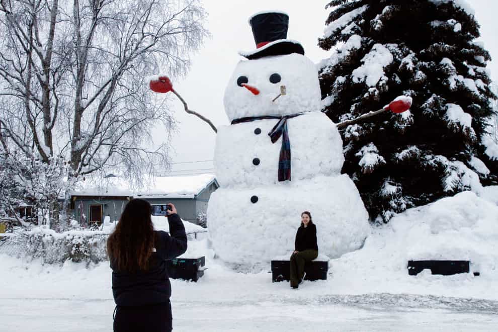 A woman takes a photo of a giant snowman Anchorage, Alaska (AP Photo/Mark Thiessen, File)